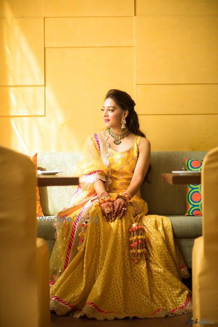 Photo of A bride in a yellow outfit and pompom kaleere for her mehndi