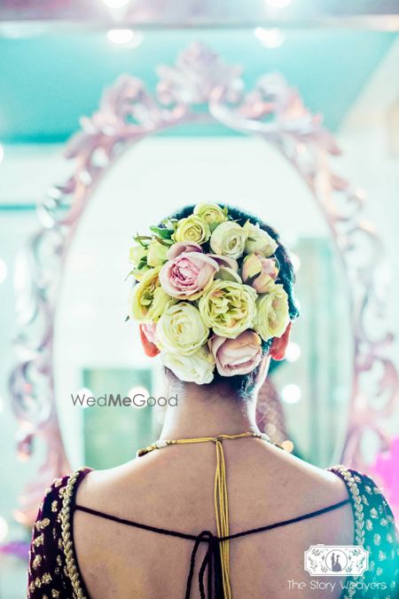 Photo of Unique bridal bun with big yellow and pink roses contrasting with dupatta