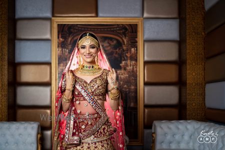 Photo of Bride wearing heavy jewellery with her maroon and gold lehenga