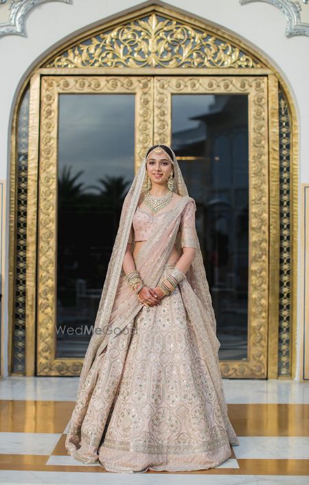 Photo of A bride in a blush pink lehenga on her wedding day