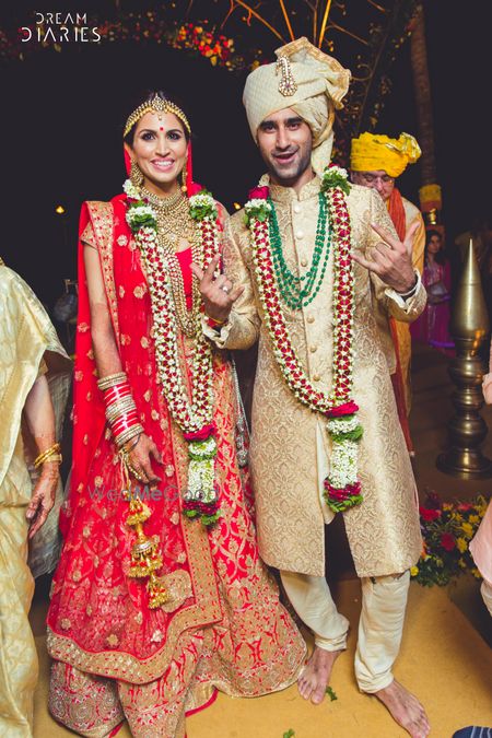 Photo of Red bridal lehenga with beige groom sherwani