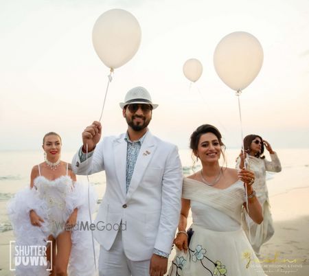 Photo of couple entering holding balloons for beach wedding