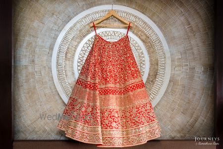 Photo of Bright Red and Gold Heavy Lehenga on a Hanger