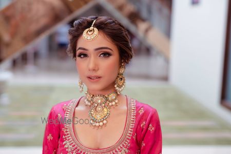 Photo of A bride in hot pink lehenga with a gold choker on her mehendi day