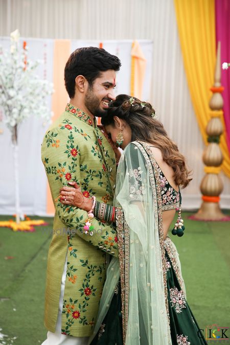 Photo of matching bride and groom in green outfits for their mehendi