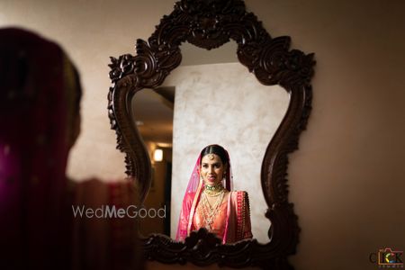 Photo of bride looking at mirror after getting ready on wedding day