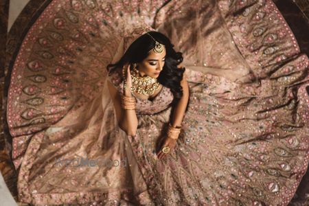 Photo of bride to be sitting with onion pink flared lehenga