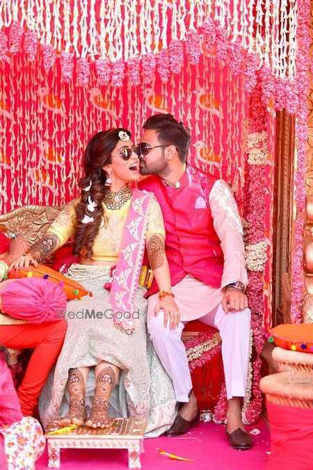 Photo of mehendi couple portrait with groom kissing the bride