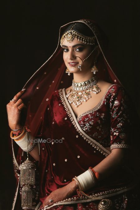 Photo of Portrait of a bride in maroon velvet lehenga