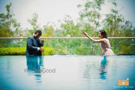 Photo of pre wedding shoot in swimming pool. bride and groom throwing water