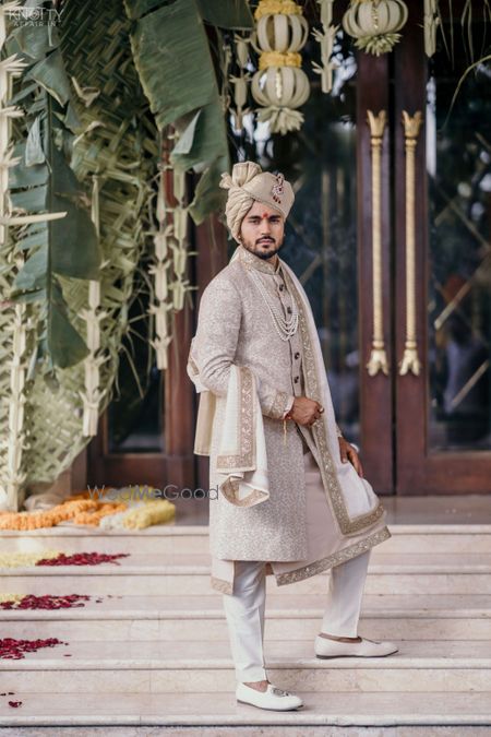 Photo of A groom dressed in white and gold sherwani on his wedding day