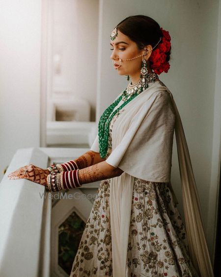 Photo of Bride wearing an ivory lehenga and emerald jewellery.