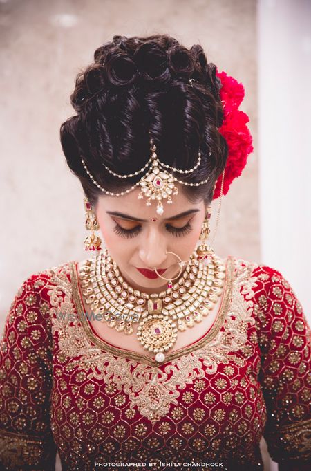 Photo of Curly Bun Bridal Hairstyle with Red Flowers on Side