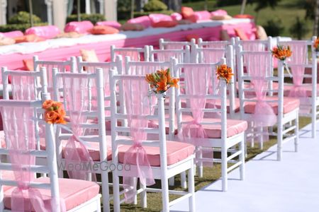 Photo of Chair backs decorated with pink ribbons and a bunch of flowers.