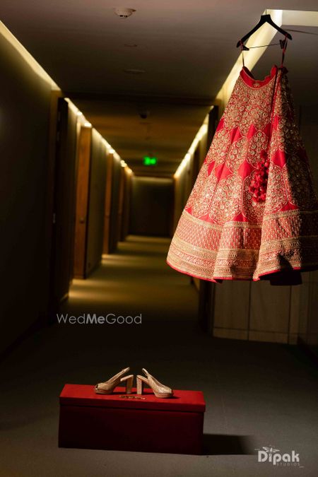 Photo of red and gold sabyasachi lehenga on hanger with box