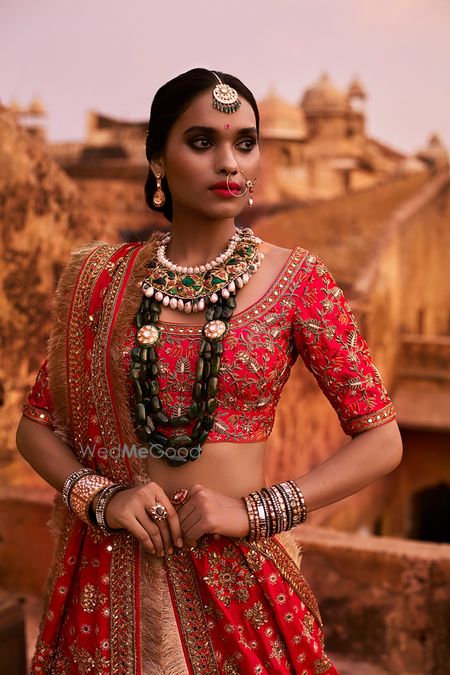 Photo of Strawberry Red Lehenga with Green Statement Jewellery