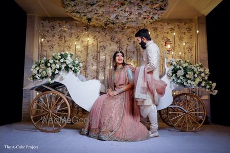 Photo of Bride and groom posing against a carriage.