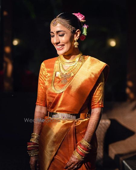 Photo of A happy bride dressed in a gold kanjeevaram.