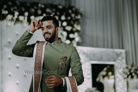 Photo of Groom wearing a sage green bandhgala with white stole